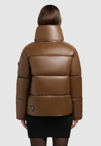 Jacheta pufosă maro cu guler înalt, finisaj lucios, design matlasat orizontal și un mic logo negru în colțul din stânga jos.