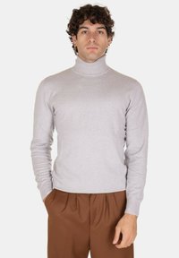 Maglione a collo alto grigio chiaro realizzato in morbido tessuto a maglia, con maniche lunghe e design aderente, abbinato a pantaloni marroni.