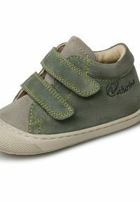 Chaussure en suède verte avec deux brides Velcro, des coutures jaunes contrastantes et une semelle en caoutchouc beige texturé. Logo de la marque visible sur le côté.