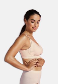 Ljusrosa bh med ribbad textur, mjuka kupor, justerbara axelband och sömlös design. Bärs med matchande högmidjade trosor.