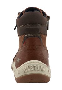 Hnědé a tmavě hnědé kožené vysoké tenisky s bílou podrážkou, viditelným šitím a červenými akcenty. Obsahují logo a texturovaný zadní díl.