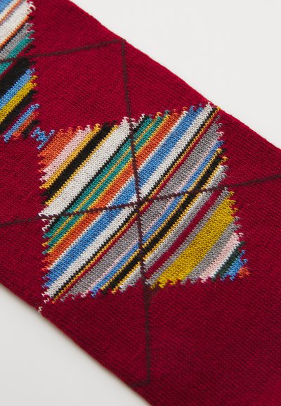 Tessuto rosso con un motivo centrale a diamante e strisce multicolori in diverse tonalità. Texture morbida con dettagli di cucitura distintivi.