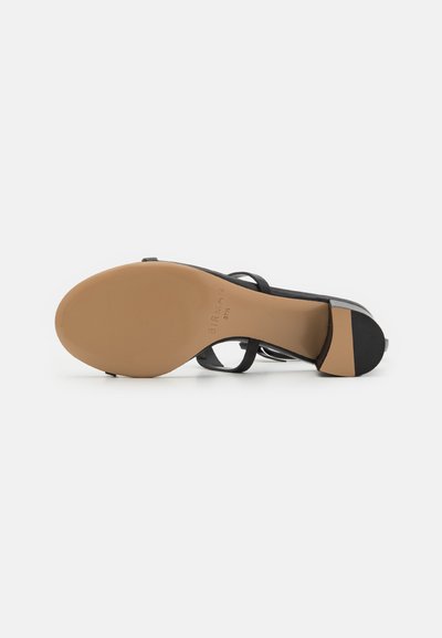 Svart klackad sandal med öppen tå och tunna remmar. Slät läderöverdel, beige gummisula med lätt klack, minimalistisk design.