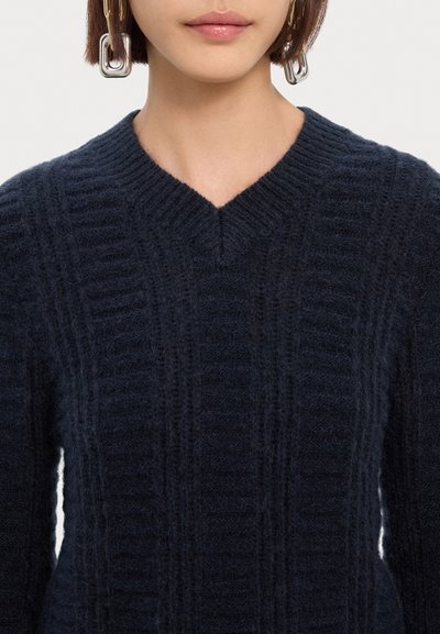 Dark navy knitted sweater with a V-neckline, featuring ribbed texture and subtle vertical patterns. Soft, cozy, and slightly oversized fit.