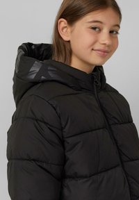 Schwarz gesteppte Pufferjacke mit Kapuze, ausgestattet mit einem Reißverschluss. Glänzende Akzente an der Kapuze sorgen für visuelle Kontraste.