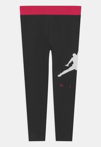 Czarne legginsy z szerokim czerwonym pasem w talii, z białą sylwetką skaczącej postaci i napisem "NI" na dolnej części nogawki w kolorze czerwonym.