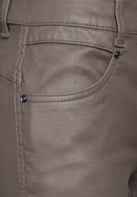 Beiga faux läderbyxor med en slät yta, sidostickningsdetalj och en liten bakficka med en silvernitar som accent.