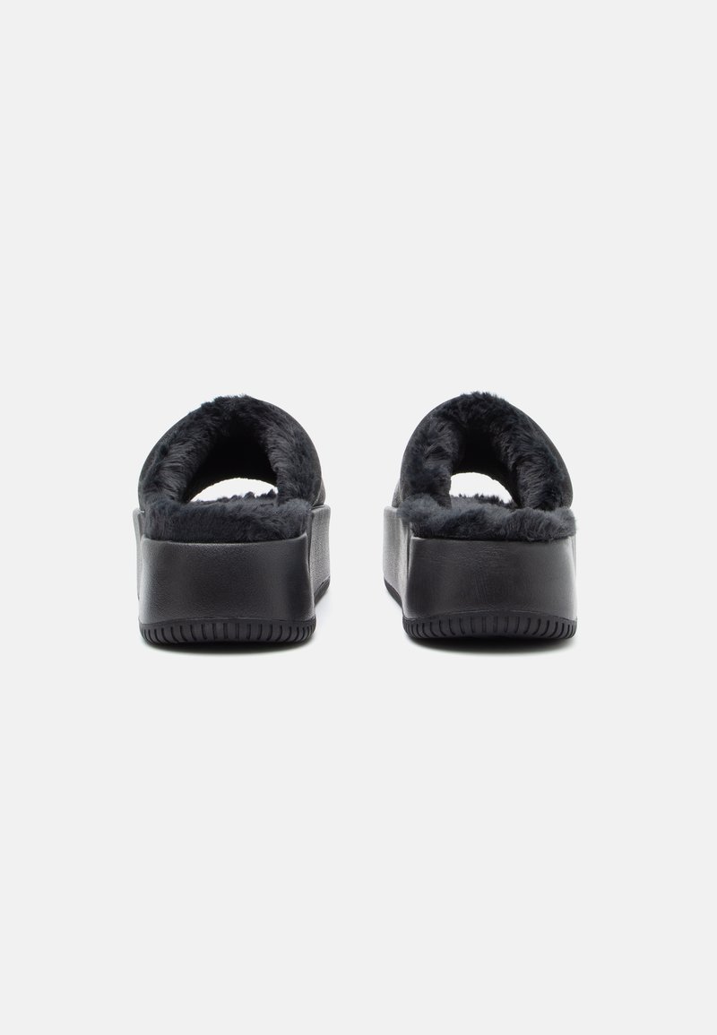 Pantofole nere con piattaforma, caratterizzate da un morbido interno foderato in pelliccia e un design con il retro aperto. La suola è sagomata per garantire grip e stabilità.