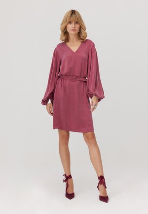 Sukienka z krótkim rękawem i dekoltem w serek w głębokim różowym kolorze, z bufiastymi rękawami, pasującym paskiem oraz prostym krojem. Uzupełniona o wysokie obcasy.