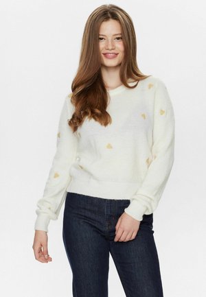 Weißer Pullover mit goldenen Herzmustern, langen Ärmeln und Rundhals, kombiniert mit dunkelblauen Jeans. Weicher Stoff, lässiges Design.