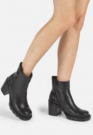 Black leather ankle boots with a chunky heel, side zipper, and textured sole. Smooth finish, mid-rise design, and rounded toe.