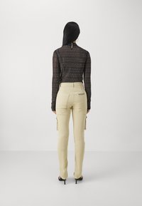 Black long-sleeve top with a textured pattern, paired with beige cargo pants featuring side pockets and brand detailing on the back.