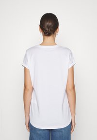 White cotton t-shirt with rolled sleeves and a rounded hem, featuring a smooth texture and relaxed fit, viewed from the back.