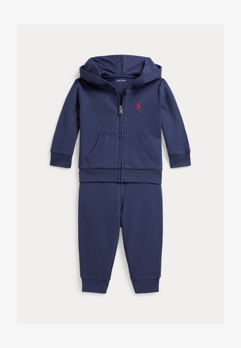 Conjunto para niño pequeño de sudadera con capucha y pantalones en azul marino, con cremallera frontal, bolsillos tipo canguro, puños acanalados y logo bordado en rojo en el pecho.