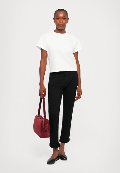 White cropped t-shirt, black roll-up jeans, and black flats; holding a maroon suede bag with gold hardware accents.