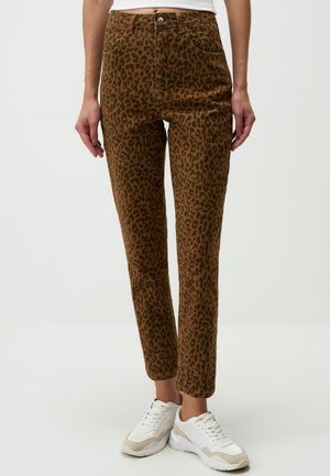 Pantalon marron à imprimé léopard avec taille haute, cinq poches et coupe droite, associé à des baskets blanches.