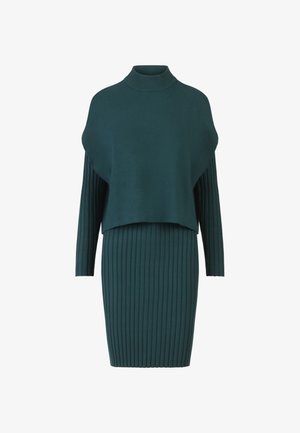 Teelegroen gebreide jurk met een hoge hals, losse bovenlaag en strakke ribbelrok. Lange mouwen en zachte textuur.