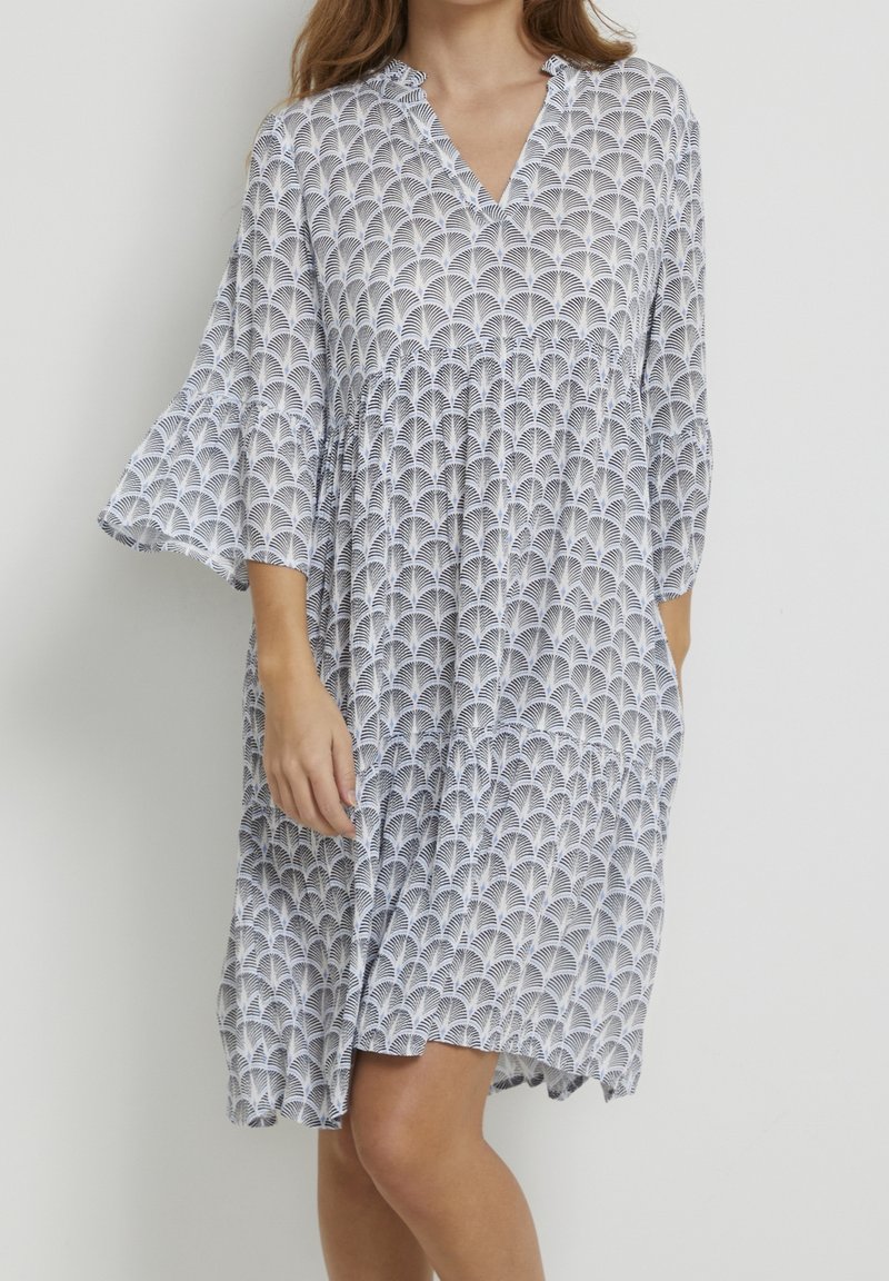 Blommönstrad klänning med V-ringning, trumpetärmar och lös passform. Tillverkad av lättviktsmaterial i blå och vita färger.