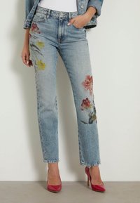 Jeans de mezclilla azul claro con bordado floral en rojo y amarillo en el frente. Diseño de pierna recta con un dobladillo deshilachado y estilo de cinco bolsillos.