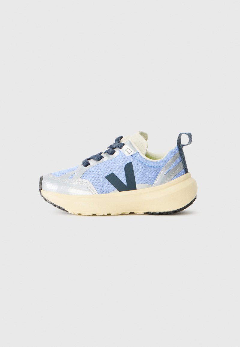 Lys blå og sølv sneaker med svart "V"-logo, svarte lisser, beige såle og hælpull-tab på en enkel hvit bakgrunn.