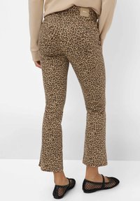 Pantalon met luipaardprint in een tan kleur, gemaakt van een textuur, zachte stof. Bevat een label aan de achterkant en is gecombineerd met zwarte mesh instappers.