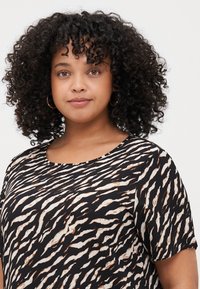 T-shirt à manches courtes avec un motif de rayures de tigre noir et blanc et des accents marron. Tissu doux avec un col rond et une coupe décontractée.