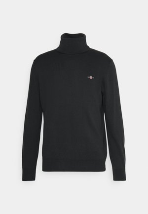 Melnā turtlenecka džemperis, izgatavots no mīkstas auduma, ar garām piedurknēm un mazu izšūtu logo uz krūšu. Gluda tekstūra, pieguļošs dizains.