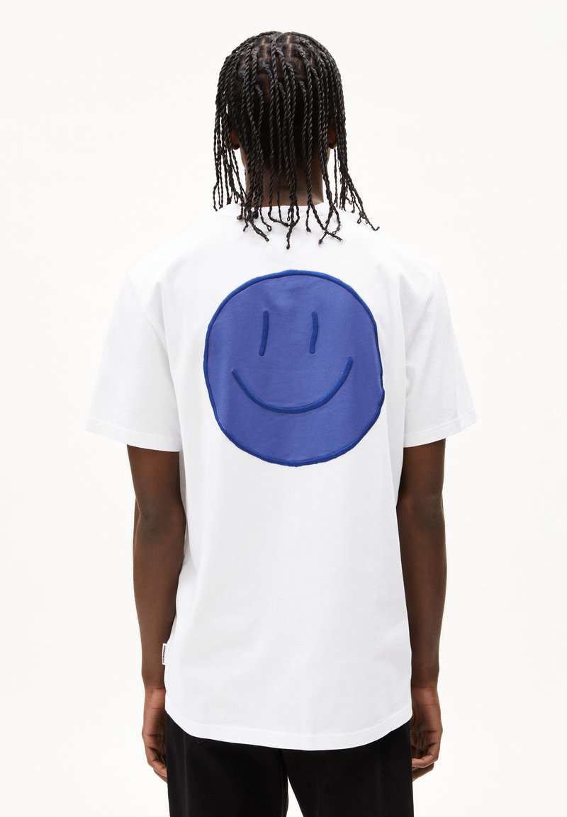 Weißes Baumwoll-T-Shirt mit einem großen blauen gestickten Smiley-Gesicht auf dem Rücken, kurzen Ärmeln und einem Rundhalsausschnitt.