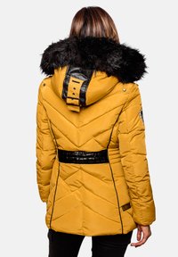 Yellow puffer jacket with a black faux fur hood, diagonal quilting, black accents, and a belted waist, featuring a logo patch on the sleeve.