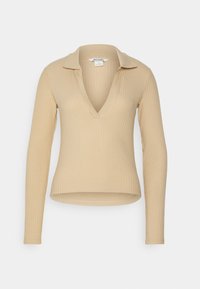 Beige ribbad långärmad topp med en djup V-ringning och en vikt krage. Tyget har en mjuk textur och en figurnära silhuett.