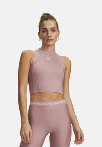 Lichtroze geribd crop-top met een hoge halslijn en mouwloos ontwerp. Voorzien van een logo op de borst en bijpassende strakke legging in dezelfde kleur.