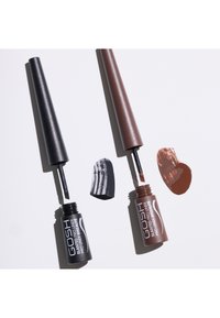 Deux tubes d'eyeliner GOSH Slanted Pro Liner ouverts, l'un contenant un eyeliner noir et l'autre un eyeliner marron, chacun montrant une trace de couleur.