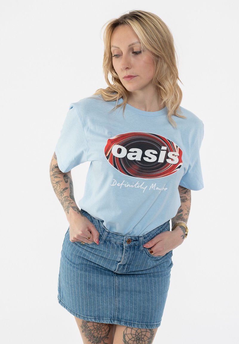 Light blue cotton T-shirt with a circular logo in red and black, reading "oasis" and "Definitely Maybe," paired with a denim skirt with stripes.