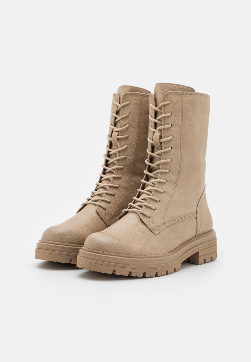 Beige Schnürstiefeletten aus strukturierter Materialwahl mit runder Zehenpartie, dicker Sohle und auffälligen Steppdetails.