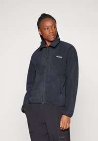 Navy Fleecejacke mit Reißverschluss, langen Ärmeln, hohem Kragen und zwei Seitentaschen; verfügt über ein kontrastierendes Panel an der Brust und ein Logodetail.