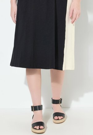Schwarz- und cremefarbener, Farbe-blockierter Kleid mit bequemer Passform, kombiniert mit schwarzen Espadrillesandalen mit Knöchelriemen und geflochtenen Sohlen.