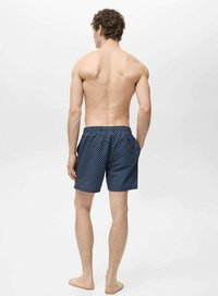 Costum de baie navy cu buline albe, talie elastică și buzunare. Material ușor și lungime până la mijlocul coapsei.