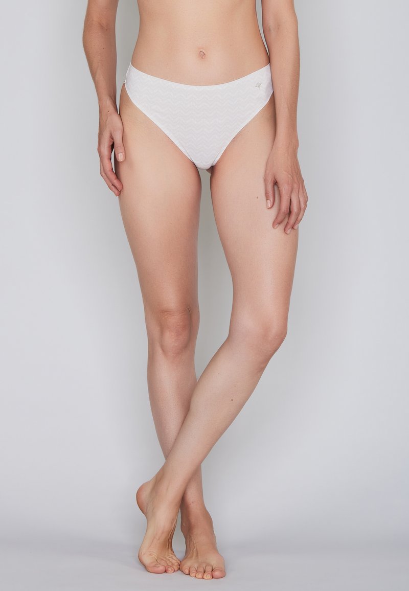 White cotton bikini briefs with a zigzag pattern, low-rise design, smooth texture, and minimal stitching detail at the waistband.