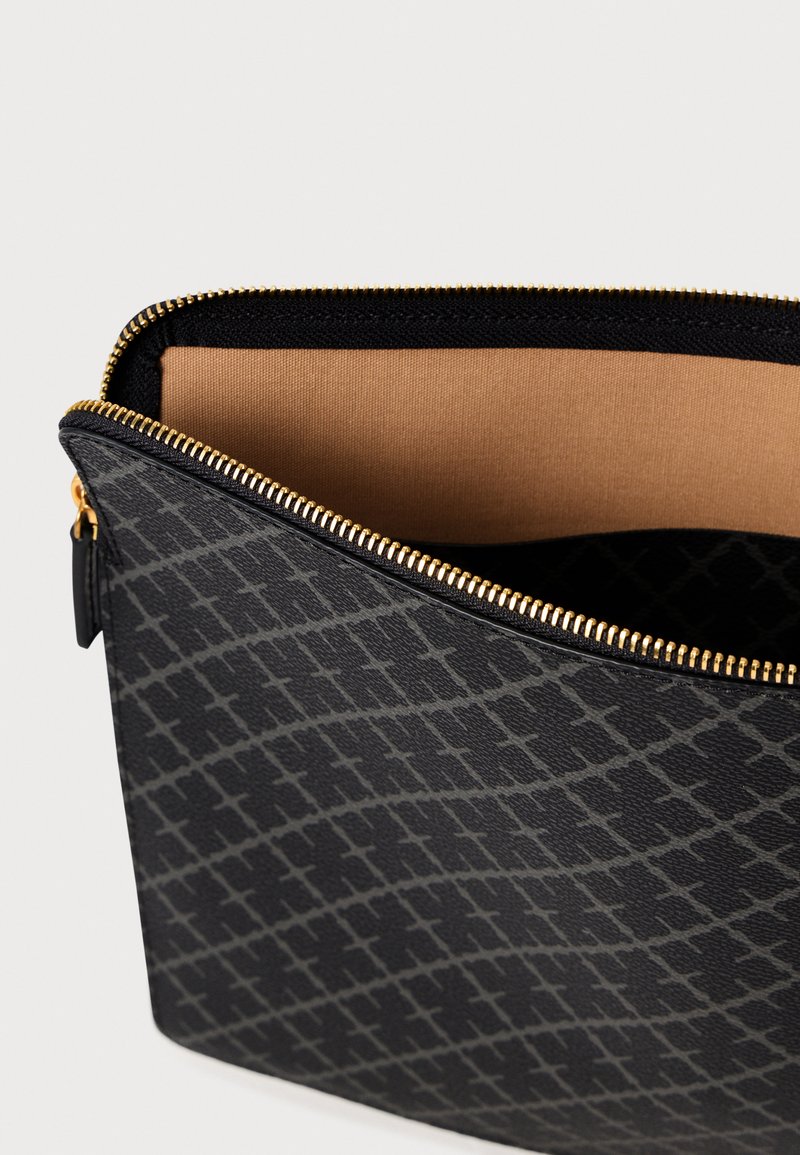 Bolsa con cremallera negra hecha de material texturizado, con un patrón geométrico. El interior es de color beige con acabado suave y herrajes de cremallera dorados.