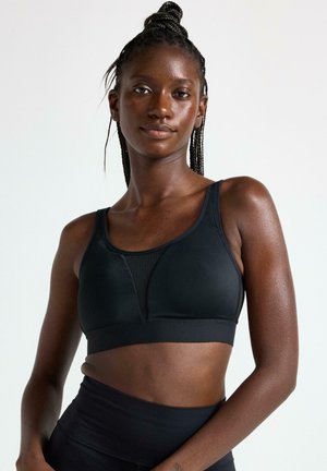 Sort sports-bh med sømløst design, der har en mesh-panel foran og brede stropper. Glat tekstur og tætsiddende form.