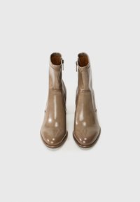 Brown leather ankle boots with a glossy finish, pointed toe, side zippers, and a structured silhouette. Rubber sole for traction.