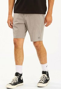 Pantalones cortos grises fabricados con un material ligero, que cuentan con una sutil textura, bolsillos laterales y un pequeño parche de logo en la pierna izquierda.