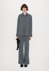 Navy and white striped button-up shirt paired with matching wide-leg pants. Textured fabric with a relaxed fit, featuring a chest pocket.