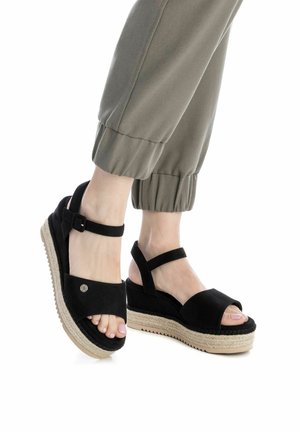 Sandalias de plataforma negras de espadrille con textura de ante, punta destalonada y correa en el tobillo. El tacón de cuña envuelto en yute añade altura y contraste.