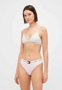 Vaalea harmaa kolmion muotoinen bralette, jossa on ohuet hihnat, yhdistettynä vaaleanpunaiseen bikinitaskuhousuihin, joissa on brändätty joustava vyötärönauha. Pehmeä, sileä rakenne.