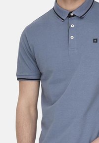 Hellblaues Poloshirt mit klassischem Kragen, einer Drei-Knopf-Leiste und kontrastierenden dunkelblauen Akzenten am Kragen und an den Ärmeln.