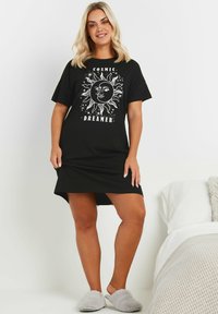Abito t-shirt in cotone nero con una grafica bianca a forma di sole e la scritta "COSMIC DREAMER". Maniche corte, vestibilità comoda e orlo arrotondato.