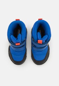 Bottes bleues pour enfants avec semelles noires, présentant un design étanche, des bandes Velcro et un accent rouge vif sur la languette.