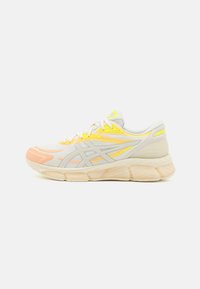 Scarpa da corsa leggera con tomaia in mesh traspirante, accenti gialli e arancioni, suola intermedia beige imbottita e suola esterna in gomma.