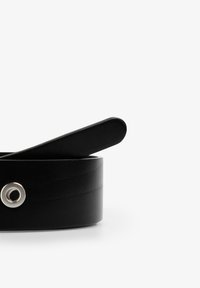 Cinturón de cuero negro con una textura suave, con un extremo redondeado y un detalle de ojal plateado. Diseño sencillo y minimalista.
